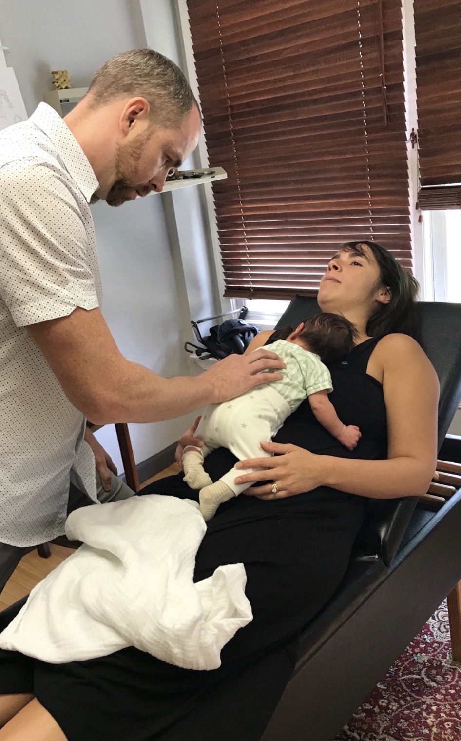 Dr. Tom adjusting an infant resting on mom's chest